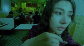 Movie still from “Fallen Angels” (1995), directed by Kar-Wai Wong – A woman is sitting at a table in front of a group of people; Close Up shot, High angle