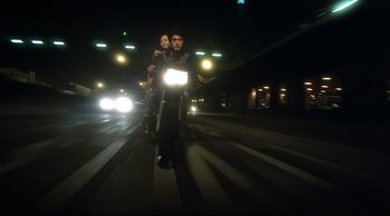 Movie still from “Fallen Angels” (1995), directed by Kar-Wai Wong – A man and a woman riding a motorcycle down a street at night; Wide shot, Low angle