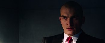 Movie still from “Hitman: Agent 47” (2015), directed by Aleksander Bach – A man in a suit and red neck tie; Close Up shot, Low angle
