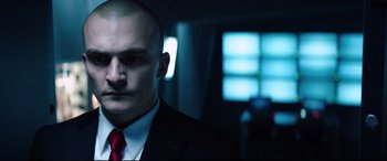 Movie still from “Hitman: Agent 47” (2015), directed by Aleksander Bach – A man in a suit and red neck tie; Close Up shot, Low angle