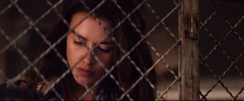 Movie still from “Hitman: Agent 47” (2015), directed by Aleksander Bach – A woman sitting in front of a chain link fence; Close Up shot, Over the shoulder angle