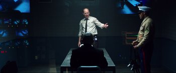 Movie still from “Hitman: Agent 47” (2015), directed by Aleksander Bach – A man standing in front of a man sitting at a table; Medium shot, Over the shoulder angle
