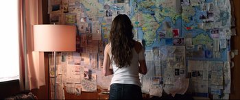 Movie still from “Hitman: Agent 47” (2015), directed by Aleksander Bach – A woman standing in front of a wall covered in papers; Medium shot, Overhead angle