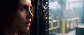 Movie still from “Hitman: Agent 47” (2015), directed by Aleksander Bach – A woman's face in front of a chain link fence; Close Up shot, Over the shoulder angle