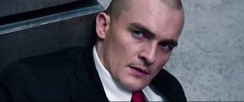 Movie still from “Hitman: Agent 47” (2015), directed by Aleksander Bach – A man in a suit and red neck tie; Close Up shot, High angle