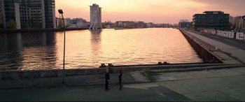 Movie still from “Hitman: Agent 47” (2015), directed by Aleksander Bach – Two men standing on the side of a road near a body of water; Extreme Wide shot, High angle