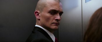 Movie still from “Hitman: Agent 47” (2015), directed by Aleksander Bach – A man in a suit and tie with a bald head; Close Up shot, Low angle