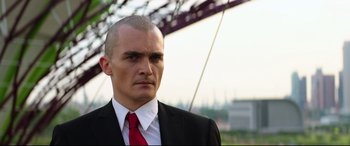 Movie still from “Hitman: Agent 47” (2015), directed by Aleksander Bach – A man in a suit and red neck tie; Close Up shot, Low angle