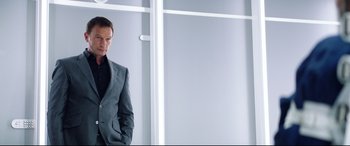 Movie still from “Hitman: Agent 47” (2015), directed by Aleksander Bach – A man in a suit standing in front of a window; Medium shot, Low angle