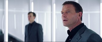 Movie still from “Hitman: Agent 47” (2015), directed by Aleksander Bach – A man in a suit and tie standing next to another man in a suit and tie; Close Up shot, Over the shoulder angle