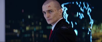 Movie still from “Hitman: Agent 47” (2015), directed by Aleksander Bach – A man in a black suit and red tie; Close Up shot, Low angle
