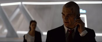 Movie still from “Hitman: Agent 47” (2015), directed by Aleksander Bach – A man in a suit and tie next to a woman in a red tie; Close Up shot, Low angle