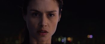 Movie still from “Hitman: Agent 47” (2015), directed by Aleksander Bach – A woman's face in front of a city skyline at night; Close Up shot, Low angle