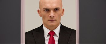 Movie still from “Hitman: Agent 47” (2015), directed by Aleksander Bach – A man in a suit and red neck tie; Close Up shot, Low angle