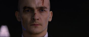 Movie still from “Hitman: Agent 47” (2015), directed by Aleksander Bach – A man with a shaved head and a blood spot on his forehead; Close Up shot, Low angle