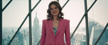 Movie still from “Gen V” (2023), created by Eric Kripke – A woman in a pink suit standing in front of a window; Medium shot, Low angle