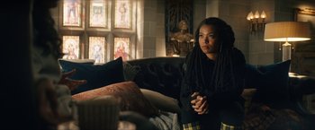 Movie still from “Gen V” (2023), created by Eric Kripke – A woman sitting on top of a couch in a living room; Medium shot, Over the shoulder angle