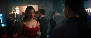 Movie still from “Gen V” (2023), created by Eric Kripke – A woman in a red dress holding a glass of champagne; Medium shot, Over the shoulder angle