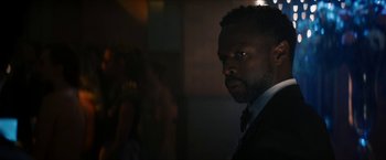 Movie still from “Gen V” (2023), created by Eric Kripke – A man wearing a suit and tie standing in a dark room; Close Up shot, Over the shoulder angle
