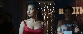 Movie still from “Gen V” (2023), created by Eric Kripke – A woman in a red dress standing in front of lights; Close Up shot, Low angle