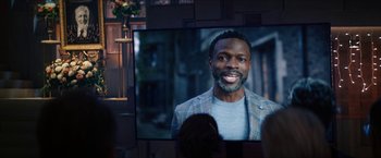 Movie still from “Gen V” (2023), created by Eric Kripke – A man is smiling in front of a television; Close Up shot, Over the shoulder angle