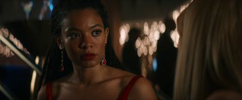 Movie still from “Gen V” (2023), created by Eric Kripke – A woman wearing a red dress and red earrings; Close Up shot, Over the shoulder angle