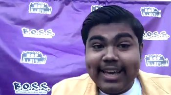 Movie still from “Homeroom” (2021), directed by Peter Nicks – A man smiling for the camera in front of a purple backdrop; Close Up shot, Low angle