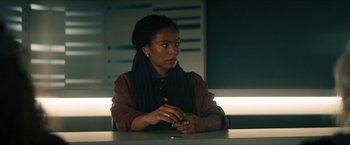 Movie still from “Gen V” (2023), created by Eric Kripke – A woman sitting at a table looking at her cell phone; Medium shot, Over the shoulder angle