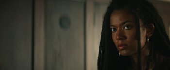 Movie still from “Gen V” (2023), created by Eric Kripke – A woman with dreads standing next to a wall; Close Up shot, Over the shoulder angle