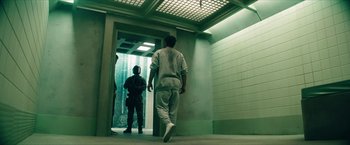 Movie still from “Gen V” (2023), created by Eric Kripke – A man walking down a hall way with another man standing next to him; Wide shot, Low angle