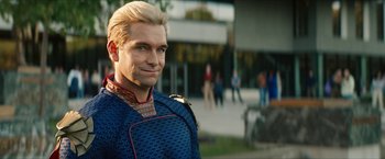 Movie still from “Gen V” (2023), created by Eric Kripke – A man with blonde hair and a blue outfit; Medium shot, Over the shoulder angle