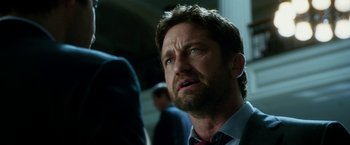 Movie still from “Geostorm” (2017), directed by Dean Devlin – A person wearing a suit and tie; Close Up shot, Low angle