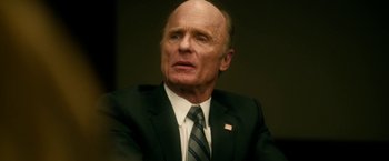 Movie still from “Geostorm” (2017), directed by Dean Devlin – An older man in a suit and tie looking to his left; Close Up shot, Low angle