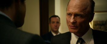 Movie still from “Geostorm” (2017), directed by Dean Devlin – A man in a suit and tie in front of another man; Close Up shot, Over the shoulder angle