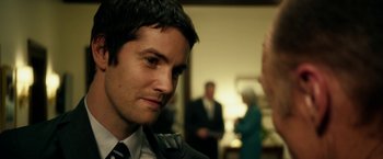 Movie still from “Geostorm” (2017), directed by Dean Devlin – A person wearing a suit and tie; Close Up shot, Over the shoulder angle