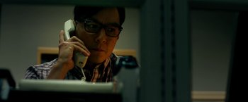 Movie still from “Geostorm” (2017), directed by Dean Devlin – A man sitting at a desk talking on a phone; Close Up shot, Low angle