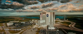 Movie still from “Geostorm” (2017), directed by Dean Devlin – An aerial view of a large building in the middle of a parking lot; Extreme Wide shot, Low angle