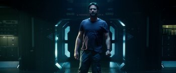 Movie still from “Geostorm” (2017), directed by Dean Devlin – A man standing in a dark room with his hands on his hips; Medium shot, Low angle