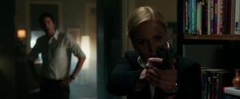 Movie still from “Geostorm” (2017), directed by Dean Devlin – A woman is holding a gun in a room; Medium shot, Over the shoulder angle