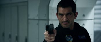 Movie still from “Geostorm” (2017), directed by Dean Devlin – A person holding a gun; Close Up shot, Over the shoulder angle