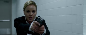 Movie still from “Geostorm” (2017), directed by Dean Devlin – A woman holding a gun in front of a brick wall; Close Up shot, Over the shoulder angle