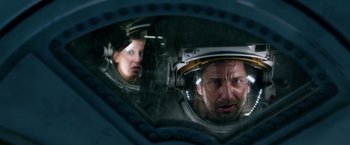 Movie still from “Geostorm” (2017), directed by Dean Devlin – A man and a woman in space suits looking at each other in a mirror; Close Up shot, Overhead angle
