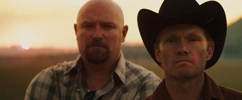Movie still from “Get the Gringo” (2012), directed by Adrian Grunberg – Two men in cowboy hats are posing for a picture; Close Up shot, Low angle
