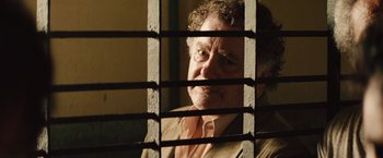 Movie still from “Get the Gringo” (2012), directed by Adrian Grunberg – An older man looking through bars of a jail cell; Close Up shot, Over the shoulder angle
