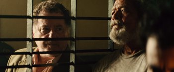 Movie still from “Get the Gringo” (2012), directed by Adrian Grunberg – Two men standing next to each other behind bars; Close Up shot, Over the shoulder angle