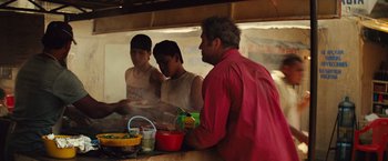 Movie still from “Get the Gringo” (2012), directed by Adrian Grunberg – Three men are standing at a counter preparing food; Medium shot, Over the shoulder angle