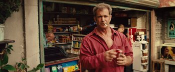 Movie still from “Get the Gringo” (2012), directed by Adrian Grunberg – A man in a red shirt is holding a can of soda; Medium shot, Over the shoulder angle