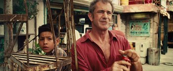 Movie still from “Get the Gringo” (2012), directed by Adrian Grunberg – A man in a red shirt is smoking a cigarette; Close Up shot, Over the shoulder angle