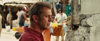 Movie still from “Get the Gringo” (2012), directed by Adrian Grunberg – A person wearing a red shirt near a tree; Close Up shot, Over the shoulder angle