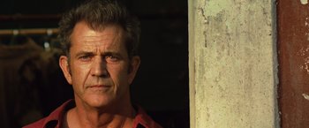 Movie still from “Get the Gringo” (2012), directed by Adrian Grunberg – A person wearing a red shirt near a wall; Close Up shot, Low angle